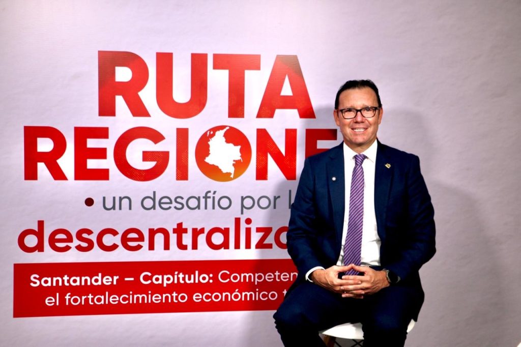 El rector sentado frente al telón del foro «Ruta Regiones: un desafío por la descentralización».
