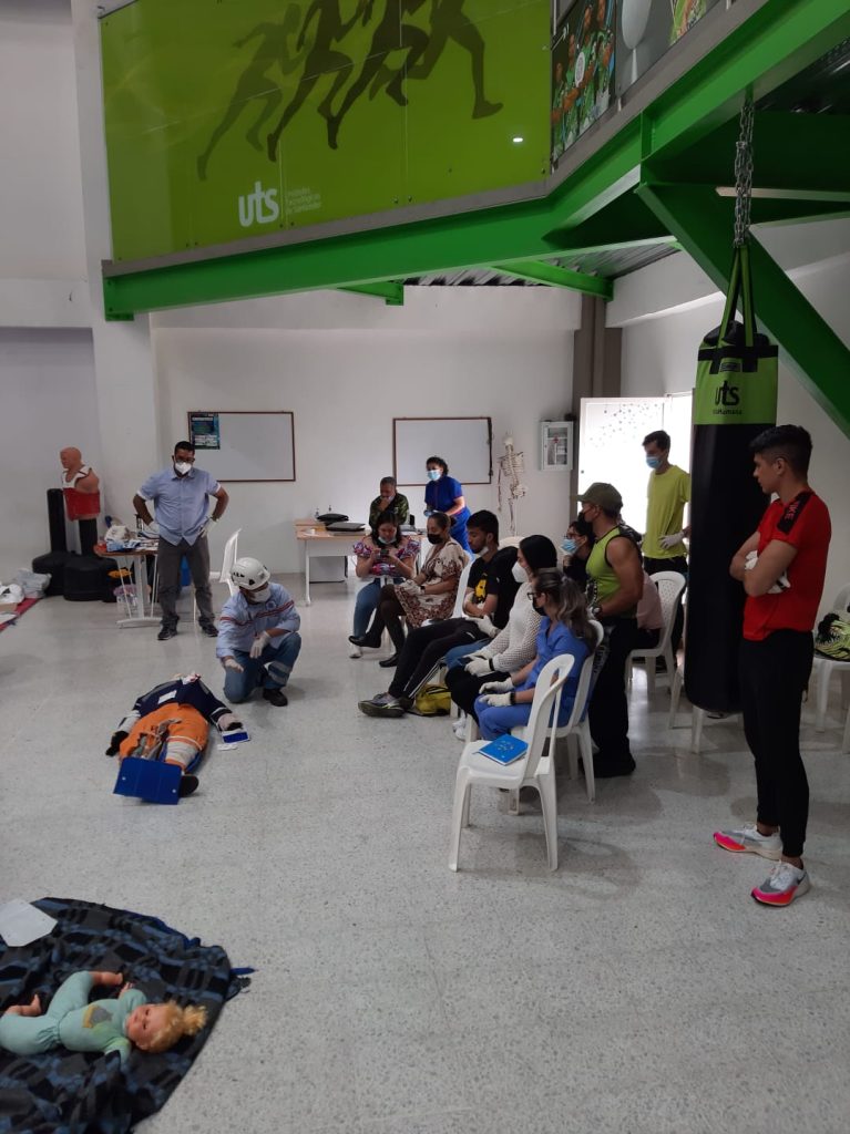 Taller de atención de emergencias con maniquíes de entrenamiento y camillas en el gimnasio del campus