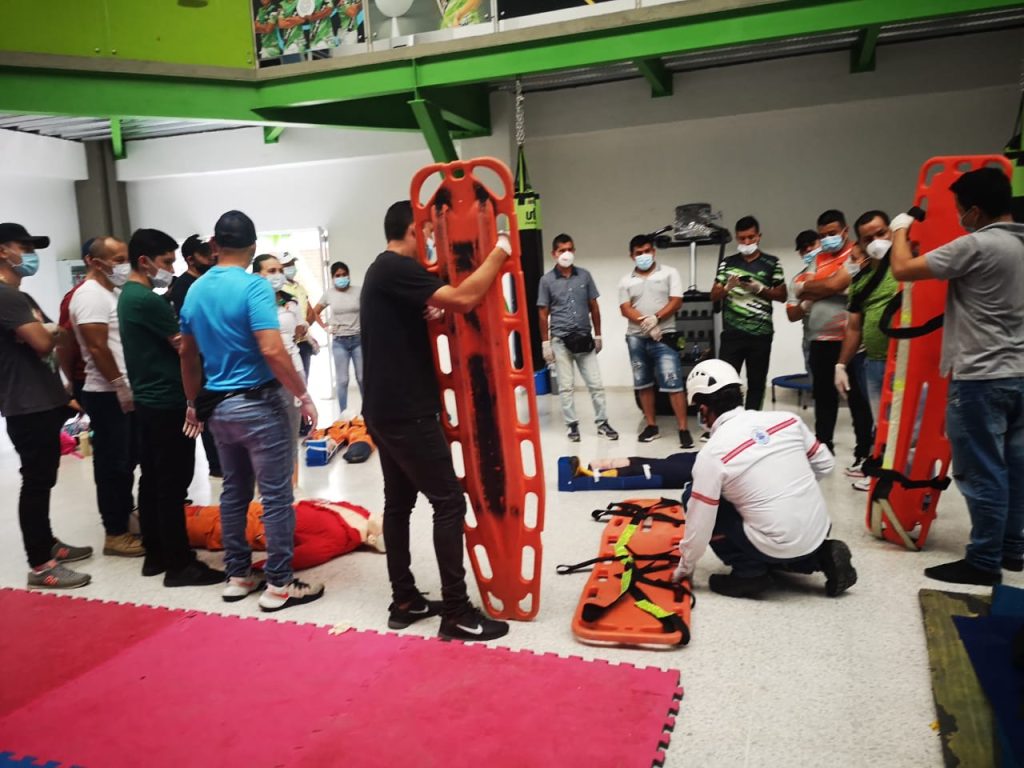 Práctica de inmovilización y traslado en camilla rígida durante un taller de primeros auxilios