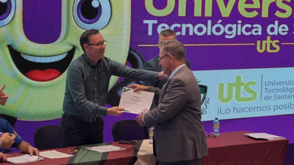 Entrega de un certificado en el escenario de un acto de la UTS