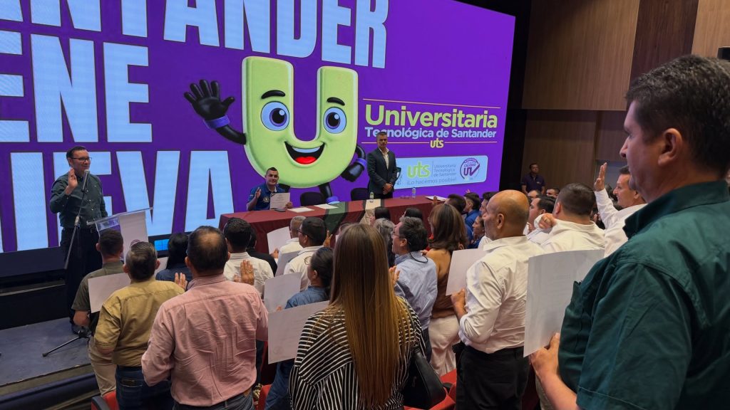 Asistentes con la mano en alto durante un acto de certificación en el auditorio