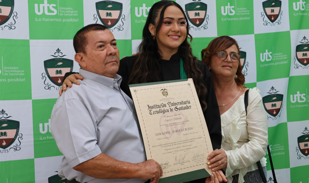 Una graduada posa con su diploma junto a su padre y su madre.
