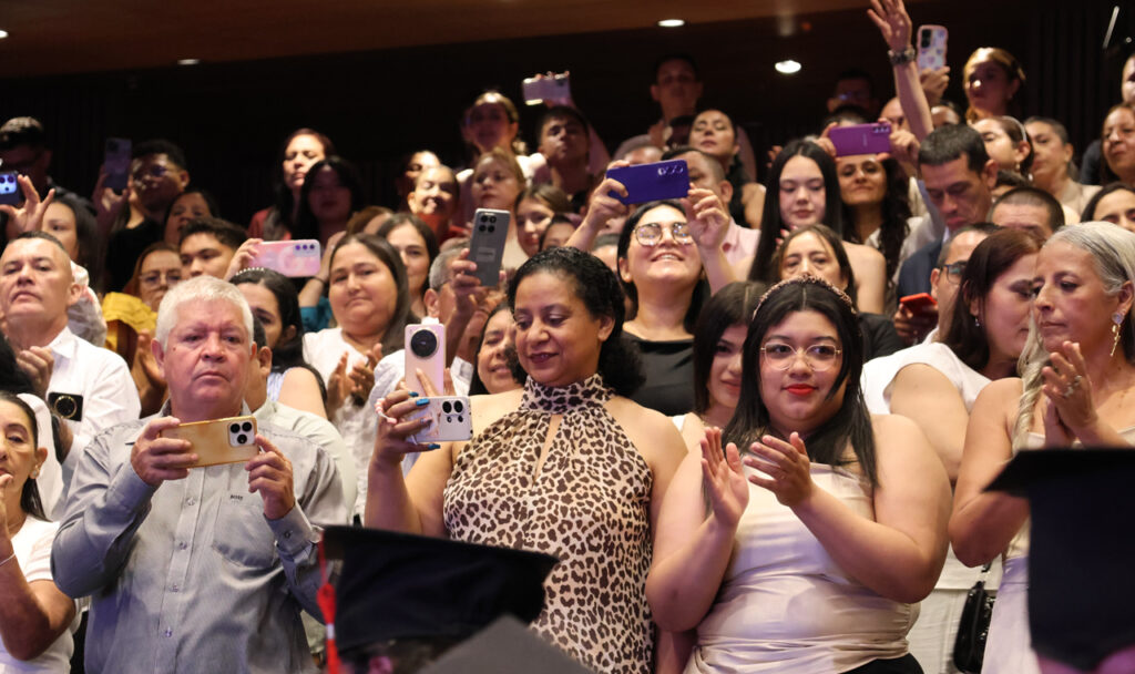Familiares aplauden y graban con sus celulares desde el público de la ceremonia.