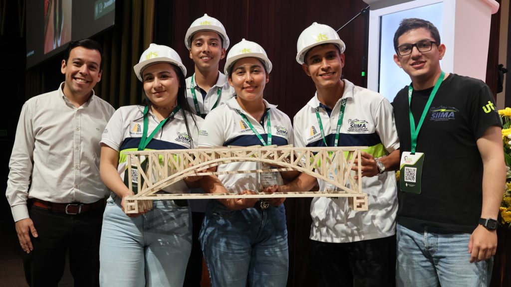 Estudiantes con casco de obra sostienen la maqueta de un puente