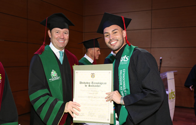 El rector, con toga, entrega el diploma a un graduando durante la ceremonia.